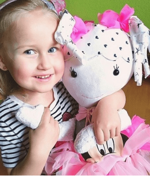 Usmiechnieta dziewczynka przytula lalke z lokami