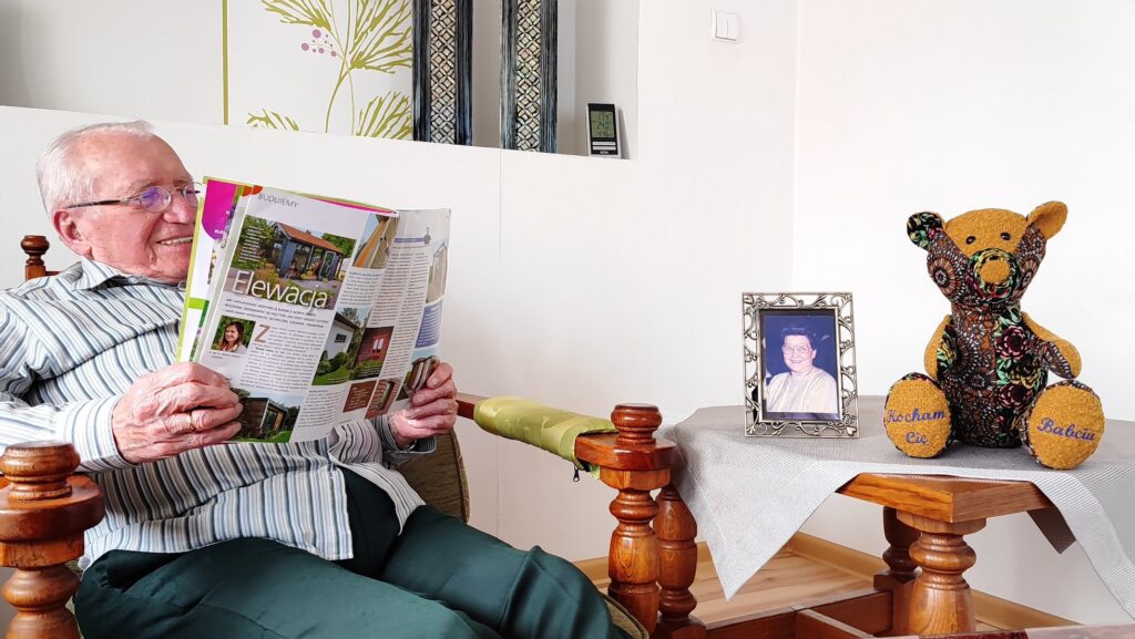 dziadek siedzi na fotelu i czyta gazete z misiem obok i zdjęciem babci drugie życie ubrań